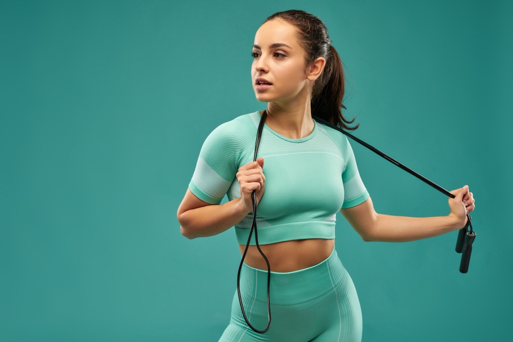 Attractive young woman in sportswear holding skipping rope
