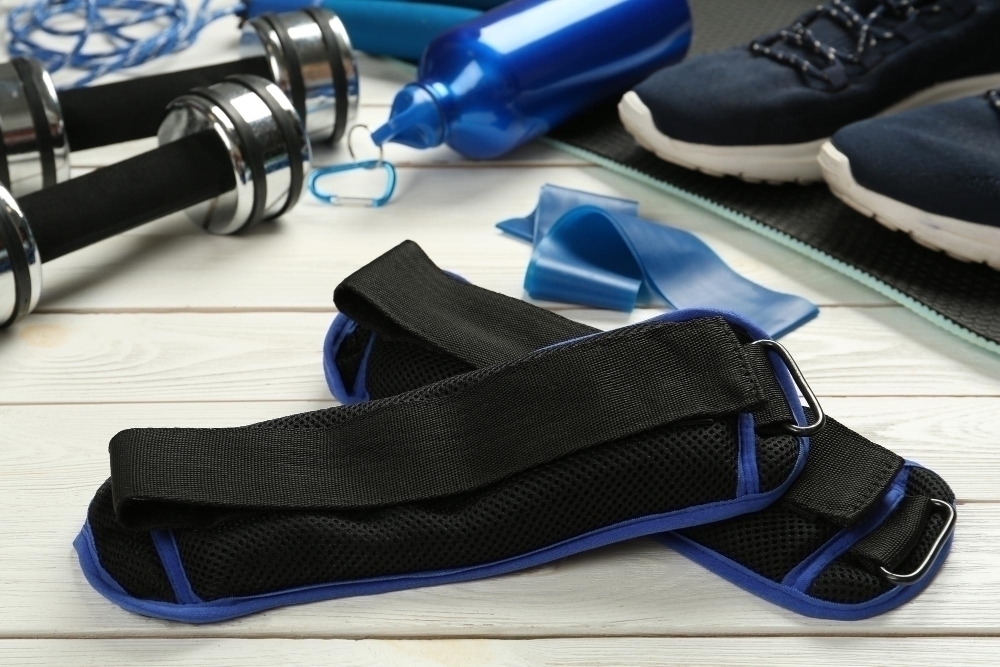 Blue ankle weights and sport equipment on white wooden table