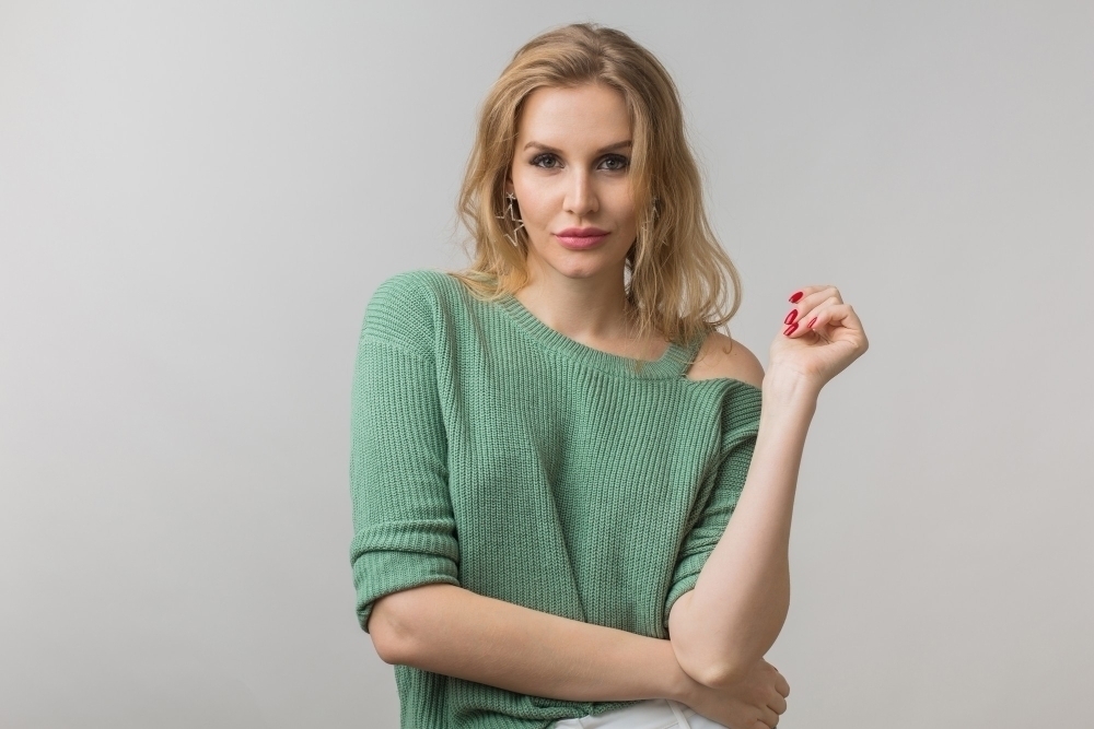 Portrait of young attractive confident sexy woman casual style green sweater independent model posing on white studio background isolated looking in camera flirty