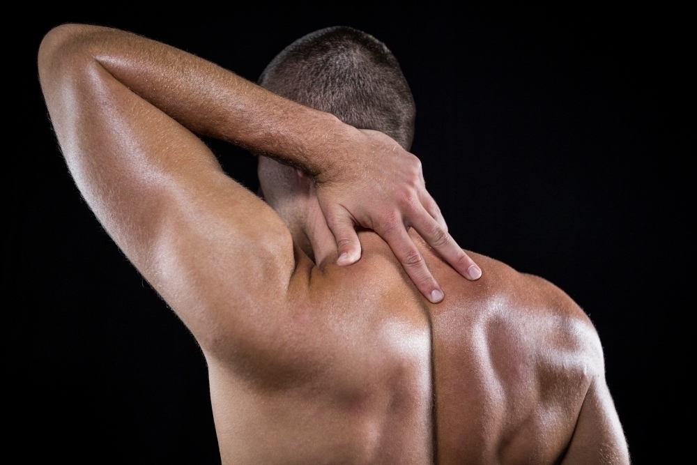 Rear view of shirtless man with neck pain