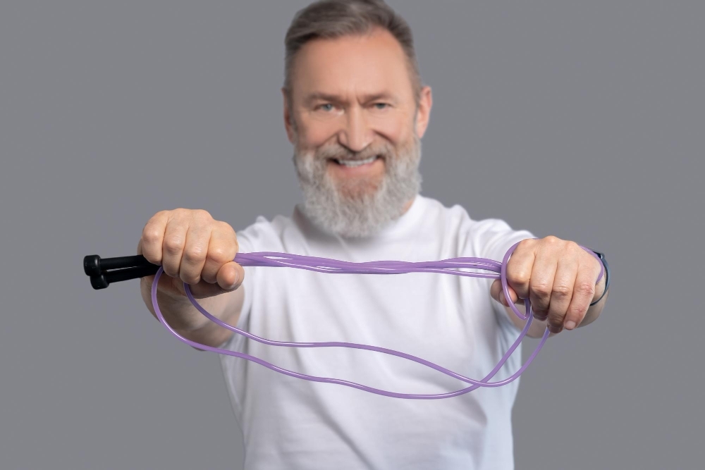 Sports. A smiling positive man with a jump rope in hands