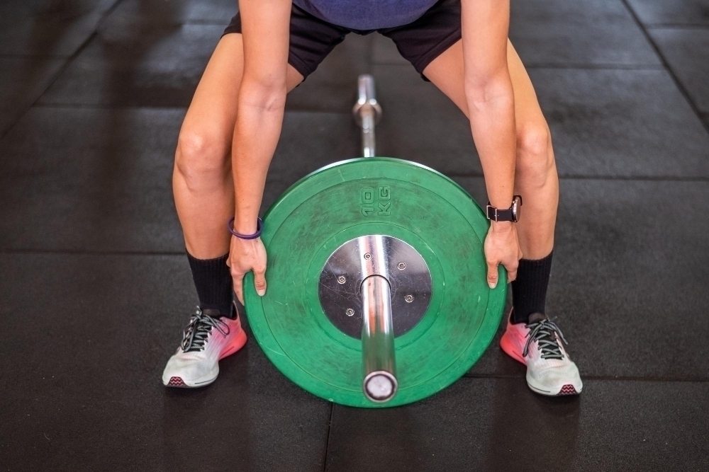 unrecognizable-sportsman-putting-heavy-discs-barbell-while-preparing-weightlifting-workout